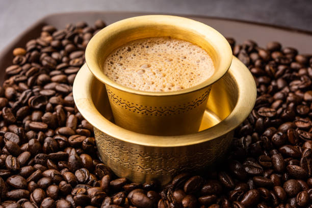 Filter coffee in a brass tumbler surrounded by coffee beans