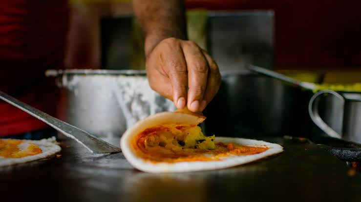 A dosa being folded fresh on the griddle